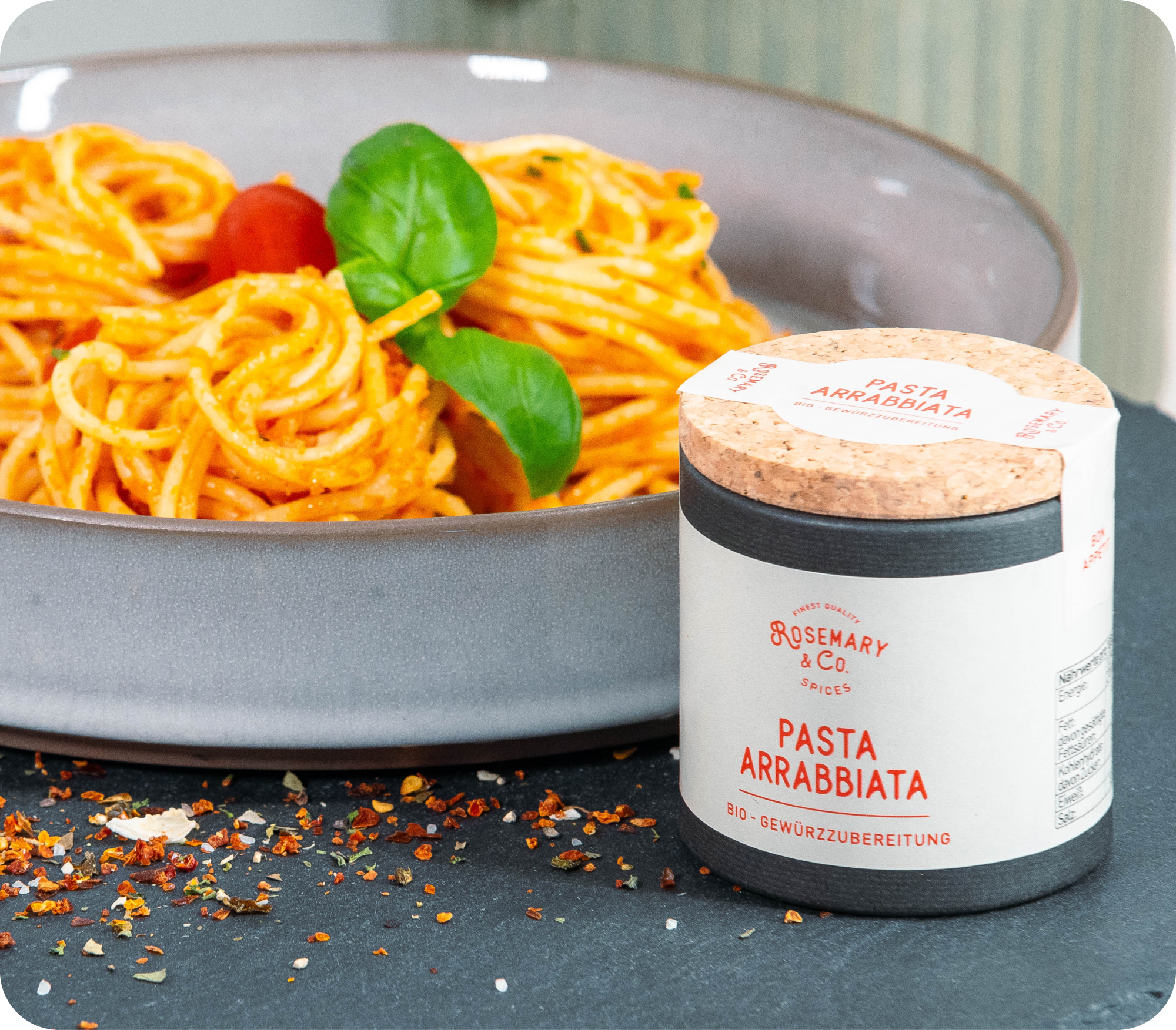 Schüssel Spaghetti mit Tomatensoße und Basilikum neben Dose Rosemary & Co. Gewürze Pasta Arrabbiata Bio