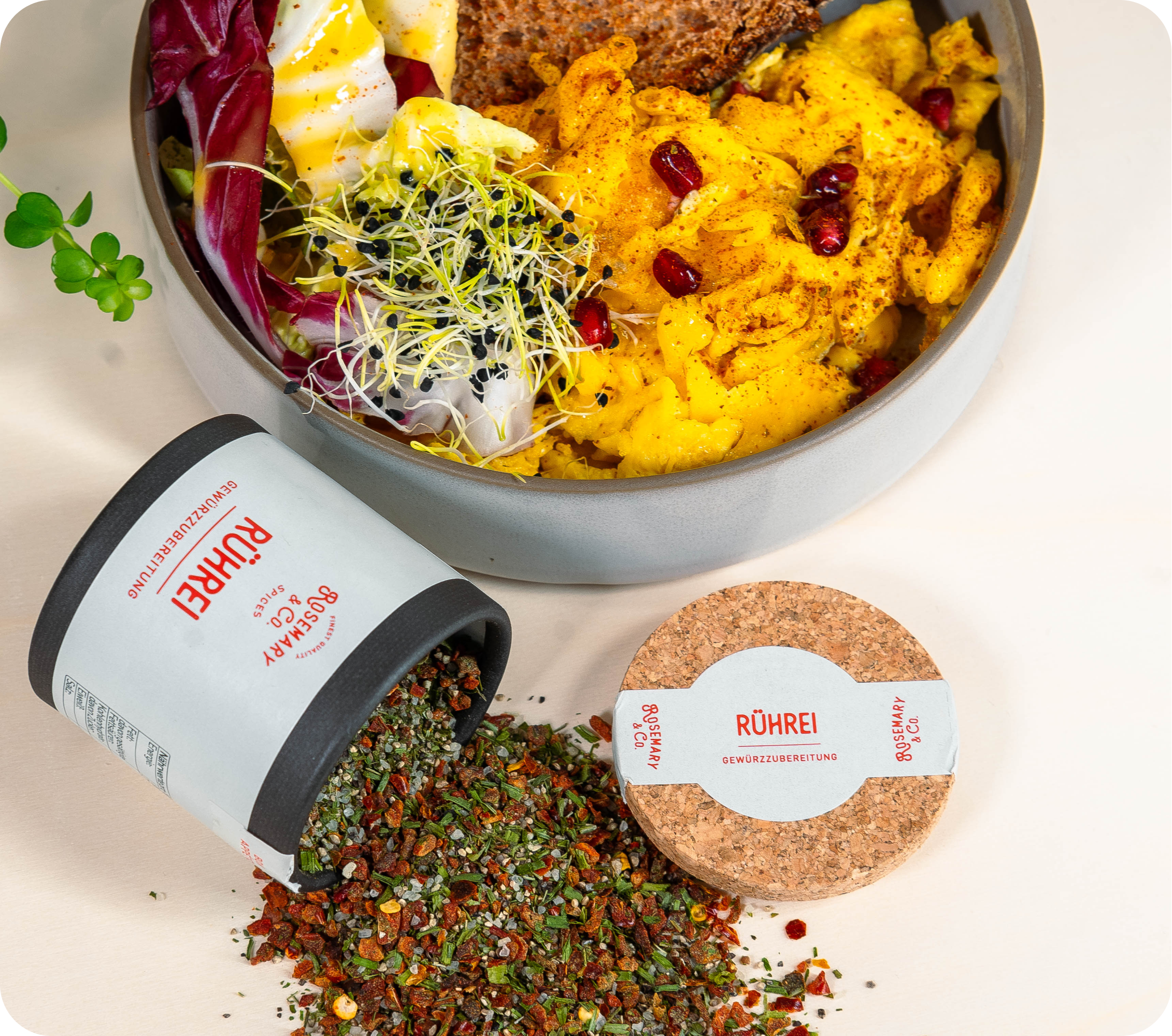 Rührei in Schüssel mit Sprossen, grünen Blättern, Brot, offene Dose Rosemary & Co. Gewürze Rührei