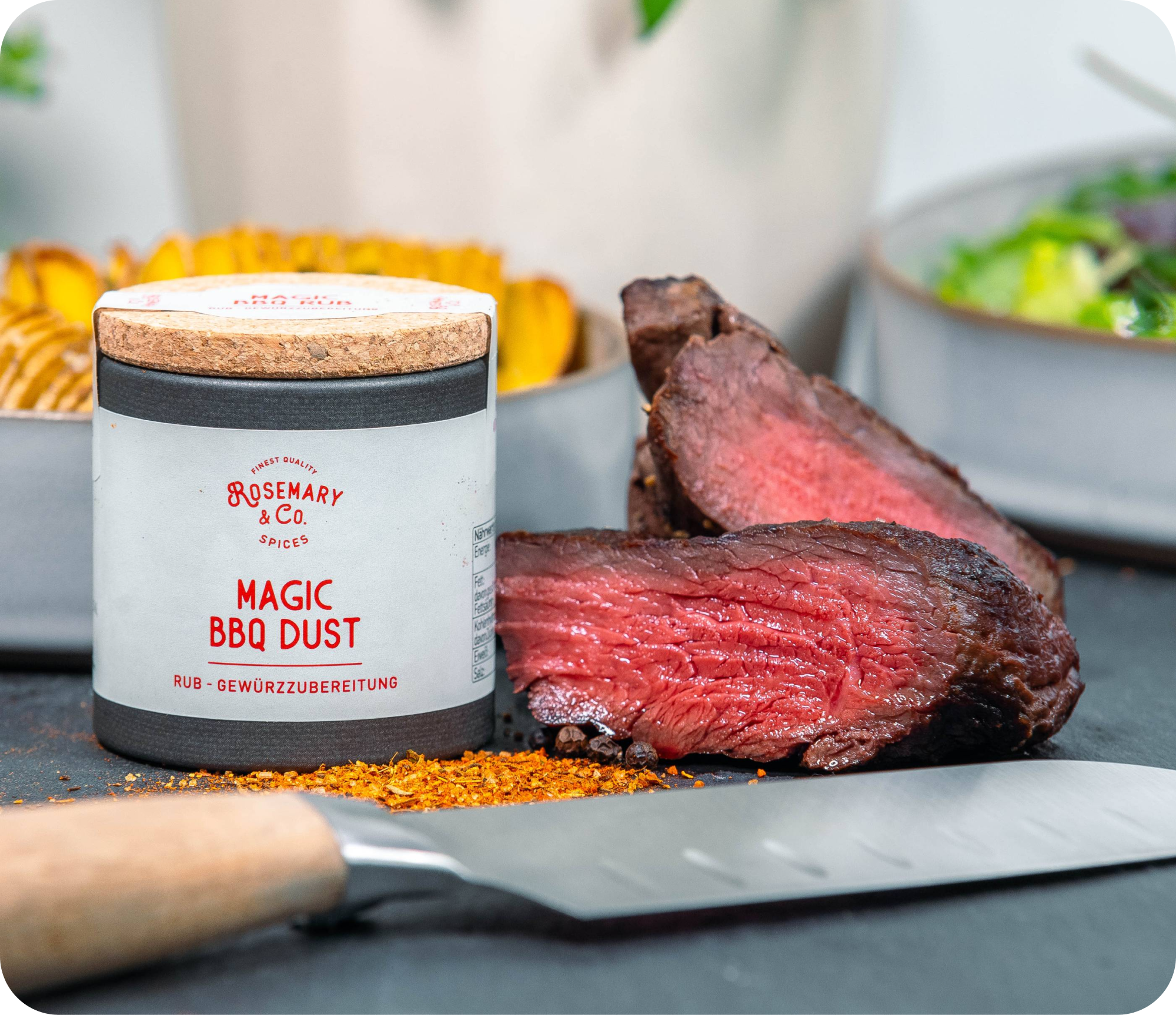 Dosis Rosemary & Co. Gewürze Magic BBQ Dust neben aufgeschnittenem Steak, Messer und Schalen mit Beilagen