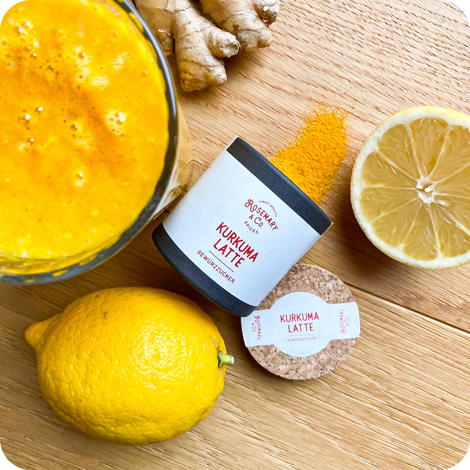 Dose Kurkuma Latte von Rosemary & Co. Gewürze, Dose Kurkumapulver, Zitronen, Ingwer und halbe Zitrone auf Holz