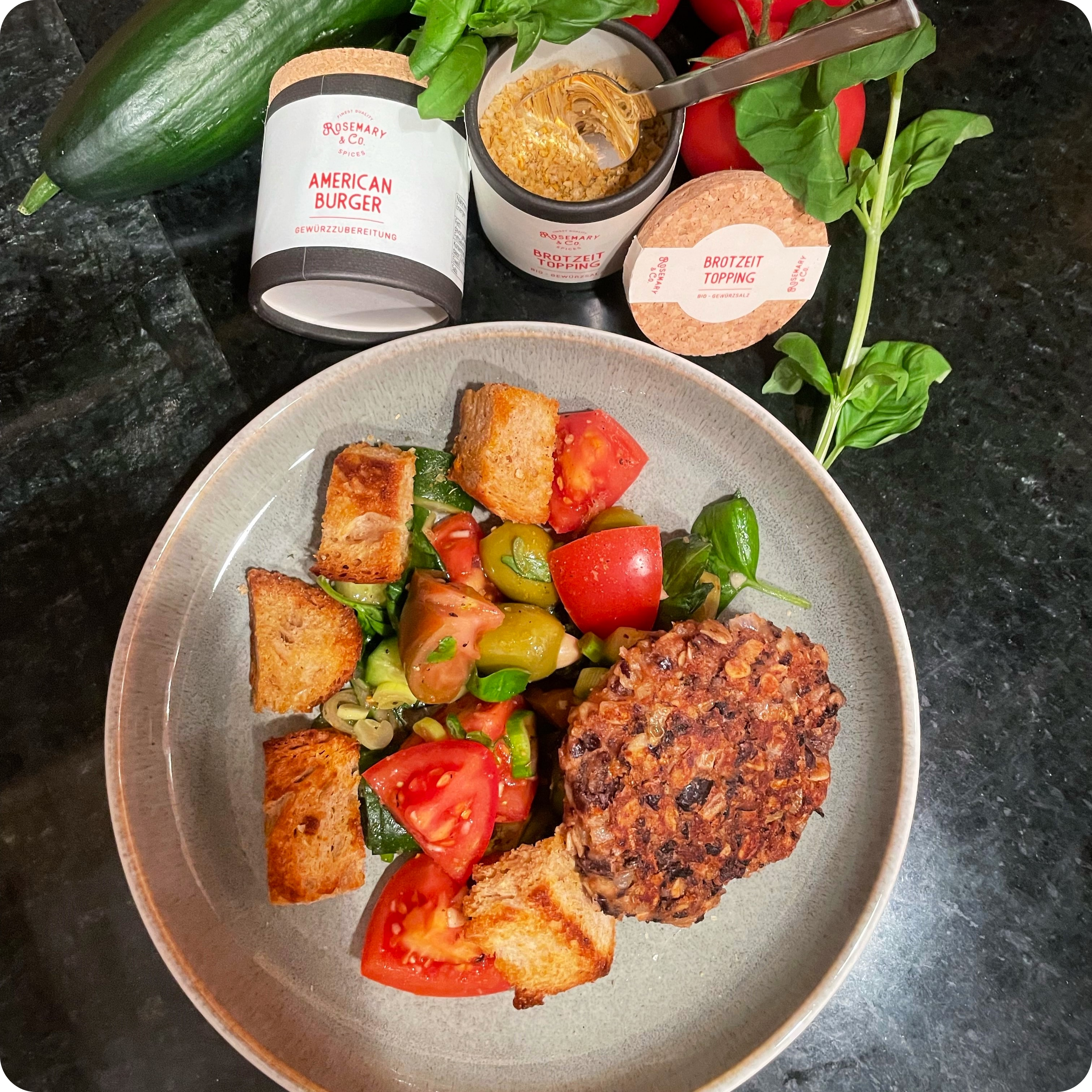 Veggie-Patty, Tomatensalat, Croutons, Basilikum und Gurke auf Teller mit Dose Rosemary & Co. The American Burger
